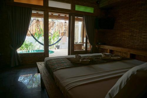 a bedroom with a large bed and a large window at Jawa House Private Villas in Gili Trawangan