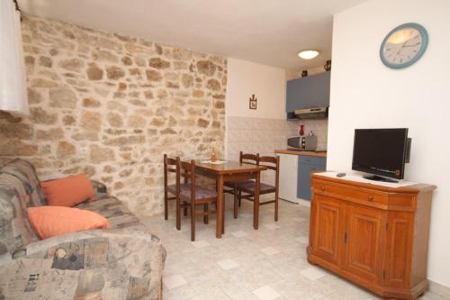 ein Wohnzimmer mit einem Sofa und einem Tisch mit einem TV in der Unterkunft Apartments by the sea Baska Voda, Makarska - 6869 in Baška Voda