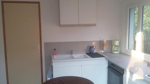 a white kitchen with a sink and a window at Pis-en-lits in Vire-sur-Lot