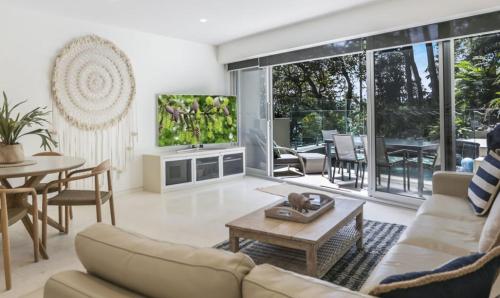a living room with a couch and a tv at Little Cove Court - Apt 4 in Noosa Heads