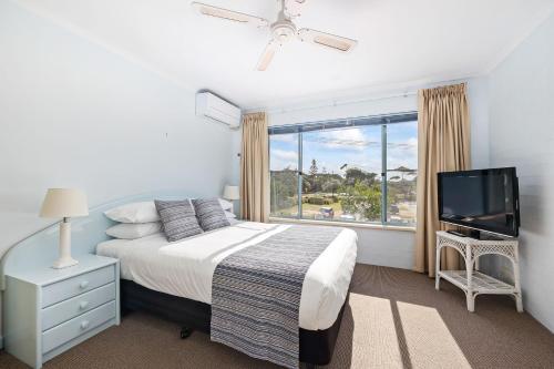 a bedroom with a bed and a tv and a window at Breakers 5 in Mollymook