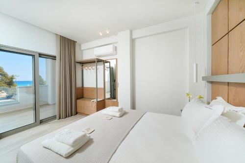 una camera da letto con un grande letto bianco e una grande finestra di Elisavet Nuevo Studios & Suites a Skala Potamias