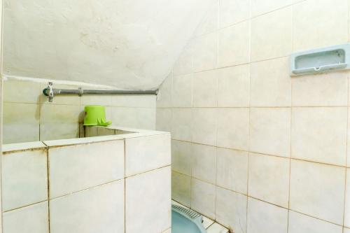 La salle de bains est pourvue de murs en carrelage blanc et de toilettes. dans l'établissement Hotel Gajah Mada, à Sukodono