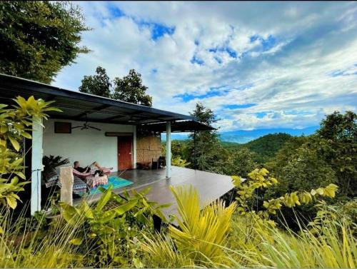 a couple sitting on the deck of a house at Monsonkeang Camping view ม่อนสันเกี๋ยง in Mae Chaem