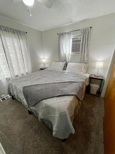 a bedroom with a large bed with two windows at Cozy Home in the Heart of Pocatello in Pocatello
