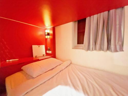 a red room with a bed and a window at Ama Hostel Bangkok in Bangkok