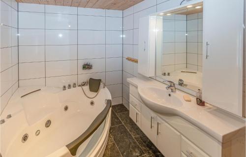 a bathroom with two sinks and a tub and a mirror at Stunning Home In Tjrhom With Wifi And 8 Bedrooms in Tjørhom