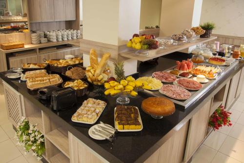 a buffet with many different types of food on a counter at Estoril Hotel in Marília
