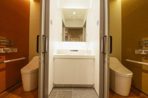 ein Badezimmer mit einem Waschbecken und 2 WCs in der Unterkunft Plum Hotel in Osaka