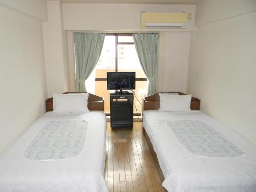 two beds in a room with a tv and a window at Weekly Green In Namba in Osaka
