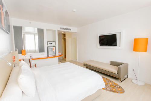 a white bedroom with a bed and a couch at HARRIS Hotel Pontianak in Pontianak