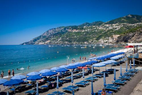 una spiaggia con ombrelloni blu e persone in acqua di Capricornio Club a Maiori
