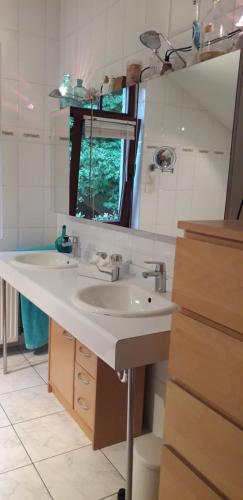 La salle de bains est pourvue d'un lavabo blanc et d'un miroir. dans l'établissement Chambre Aqualine, à Aywaille