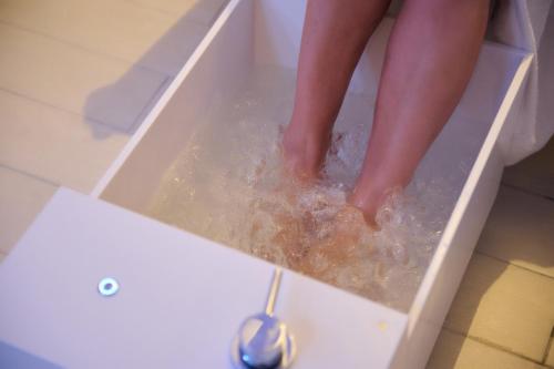 a child standing in a bath tub with their feet in water at Ludwig Boutique Hotel & Spa in Bolsena