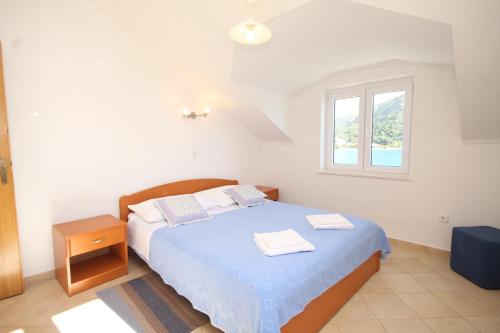 une chambre avec un lit avec des draps bleus et une fenêtre dans l'établissement Apartments by the sea Slano, Dubrovnik - 8741, à Slano