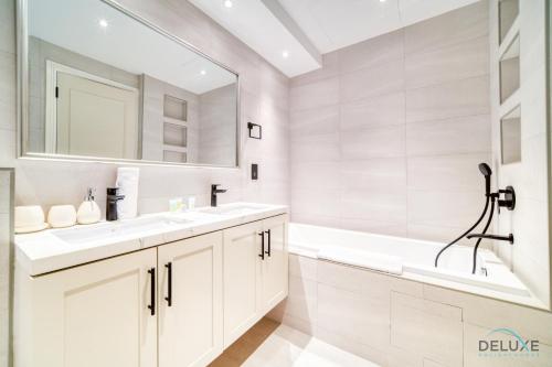 biała łazienka z 2 umywalkami i lustrem w obiekcie Phenomenal 1BR at Al Tajer E Downtown Dubai by Deluxe Holiday Homes w Dubaju