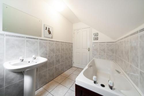 y baño blanco con lavabo y bañera. en Earnside Cottage, en Comrie