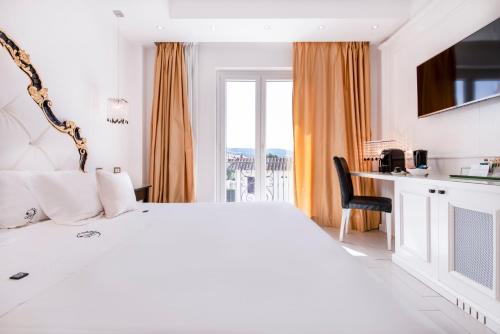 a white bedroom with a large bed and a desk at Ludwig Boutique Hotel & Spa in Bolsena
