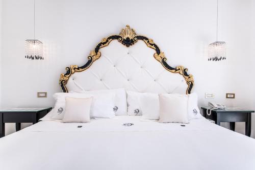 a white bed with a gold frame and white pillows at Ludwig Boutique Hotel & Spa in Bolsena