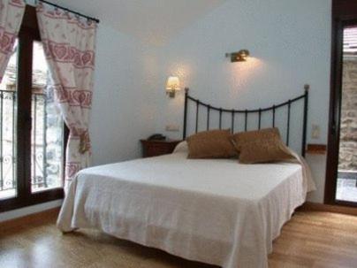 a bedroom with a bed with white sheets and windows at Hotel Villa Russell in Torla
