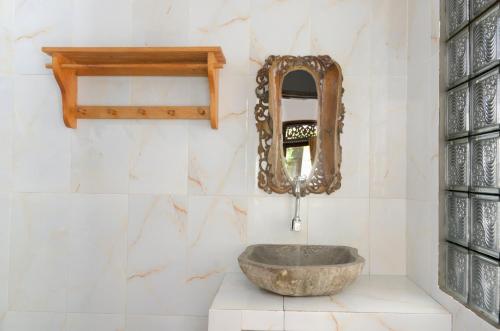 a bathroom with a stone sink and a mirror at Warna Beach Hotel in Gili Trawangan