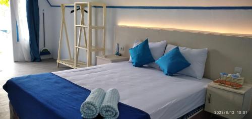 a bedroom with a large bed with blue pillows and shoes at 3 Maria Cottage in Ngurblut