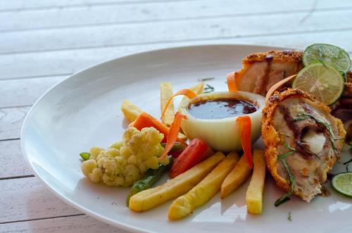 a plate of food with meat and vegetables and sauce at Warna Beach Hotel in Gili Trawangan