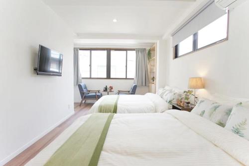 a white bedroom with two beds and a tv at dandelion house in Tokyo
