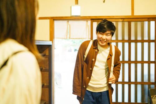 a young man standing in a room smiling at Masukichi -hostel,cafe,souvenir,guide- in Seto