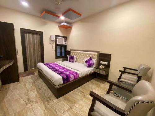 - une chambre avec un lit doté de draps violets et d'une chaise dans l'établissement Hotel Nagpal By WB Inn, à Haridwar