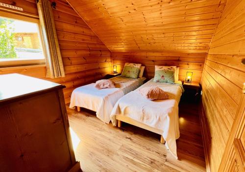 um quarto com 2 camas num chalé de madeira em Chalet de 3 chambres avec piscine partagee sauna et terrasse a Le Devoluy em Le Dévoluy
