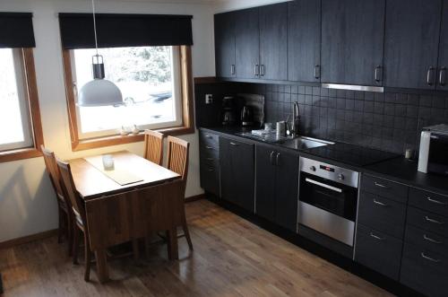 a kitchen with black cabinets and a table and a window at Skoogs Logi Lägenheter in Funäsdalen