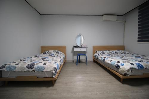 Dos camas individuales en una habitación con una mesa y una cama Sidx Sidx. en Bunk Backpackers Guesthouse en Seúl