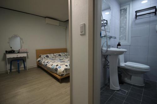 uma casa de banho com uma cama, um lavatório e um WC. em Bunk Backpackers Guesthouse em Seul