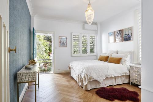 a white bedroom with a bed and a window at kookaburra beach house coogee in Sydney