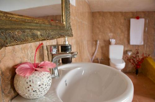 un lavabo con un jarrón con una flor rosa. en The House of Royals en Zanzíbar