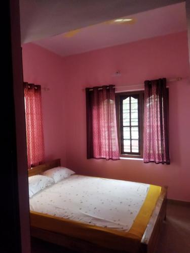 a bedroom with a bed with pink walls and a window at Hidden gem home stay -2 in Madikeri