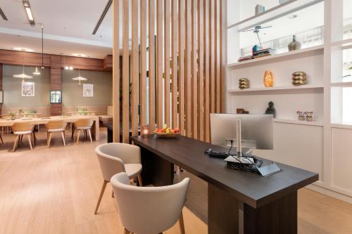 an office with a desk and chairs and a dining room at Meliá Düsseldorf in Düsseldorf
