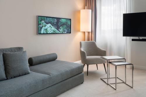 a living room with a couch and a chair and a tv at Meliá Düsseldorf in Düsseldorf