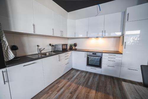 a white kitchen with wooden floors and white cabinets at Pit Stop Apartments in Cham