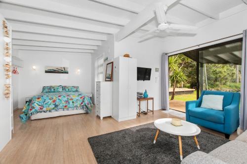 een slaapkamer met een bed en een blauwe stoel bij Bayside Beauty - Matapouri Holiday Home in Matapouri