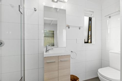 een witte badkamer met een wastafel en een toilet bij Bayside Beauty - Matapouri Holiday Home in Matapouri
