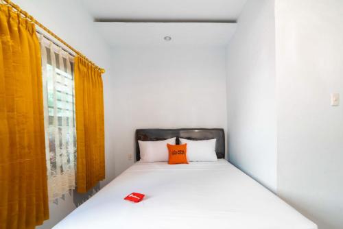 a bedroom with a bed with an orange pillow at KoolKost Syariah @ Wisma Arafah Tasikmalaya (Minimum Stays 30 Nights) in Tasikmalaya
