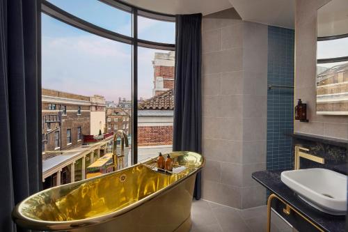 a bathroom with a tub and a large window at AMANO Covent Garden in London