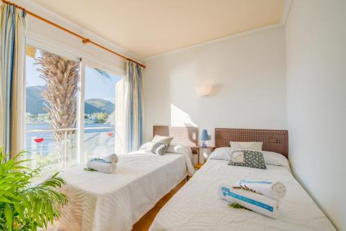 zwei Betten in einem Zimmer mit großem Fenster in der Unterkunft Ideal Property Mallorca - Lago Miguel in Port d'Alcúdia