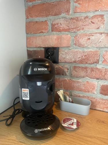 a black mixer sitting on a table next to a brick wall at Bison Apartamenty in Białystok