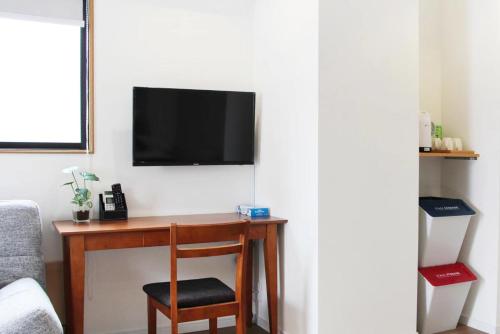 a desk with a chair and a television on a wall at dandelion house in Tokyo