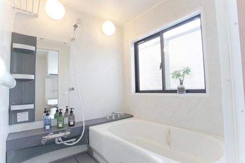 a white bathroom with a tub and a window at dandelion house in Tokyo