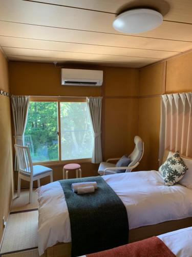 um quarto de hotel com duas camas e uma janela em Sai's House Hakuba em Hakuba