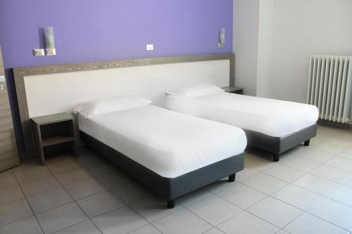 2 łóżka w pokoju z fioletowymi ścianami w obiekcie Hotel Savoia w mieście Poggio Rusco